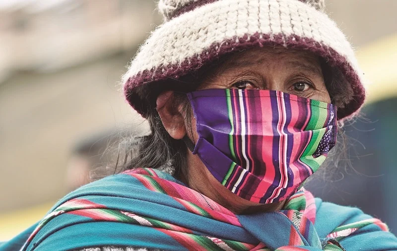 mujer mira a la camara tras una mascarilla hecha de aguayo en bolivia